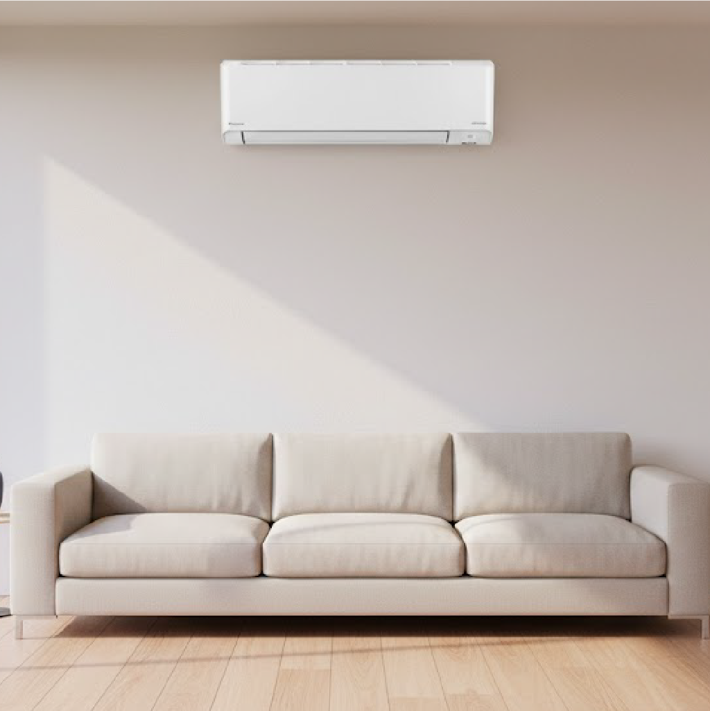 Minimalist living room with white three-seater sofa, wall-mounted air conditioner, floor-to-ceiling windows with natural light, and light wooden flooring.