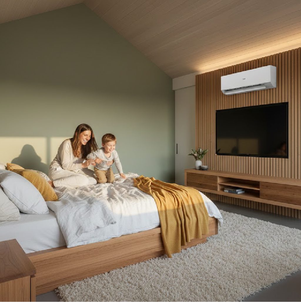 Mother and son playing on wooden platform bed in modern bedroom with vertical wood panelling, wall-mounted white AC unit.